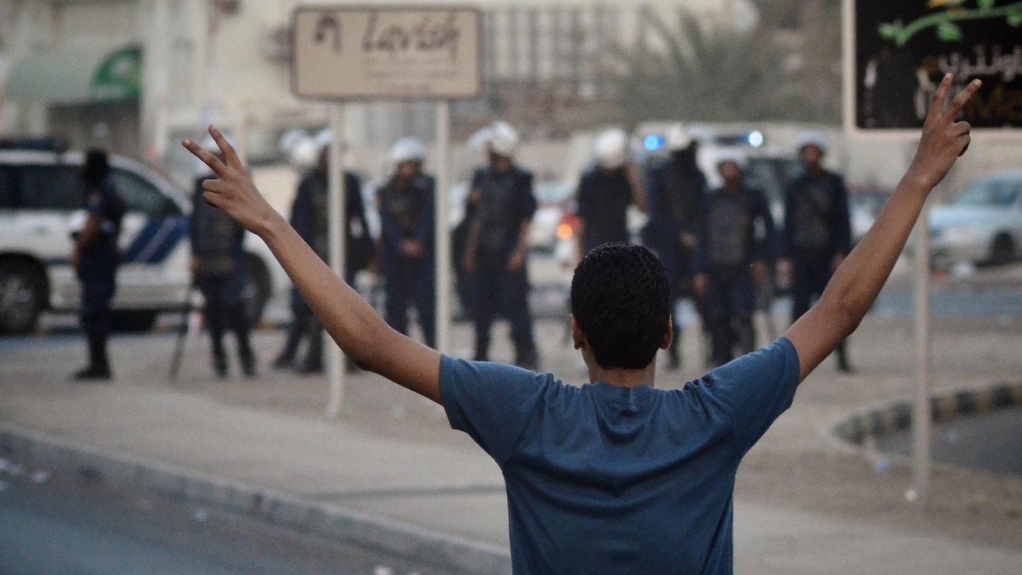 A Bahraini protester flashes a 'V' sign for victory in front of riot police during a June anti-government demonstration in Bahrain.