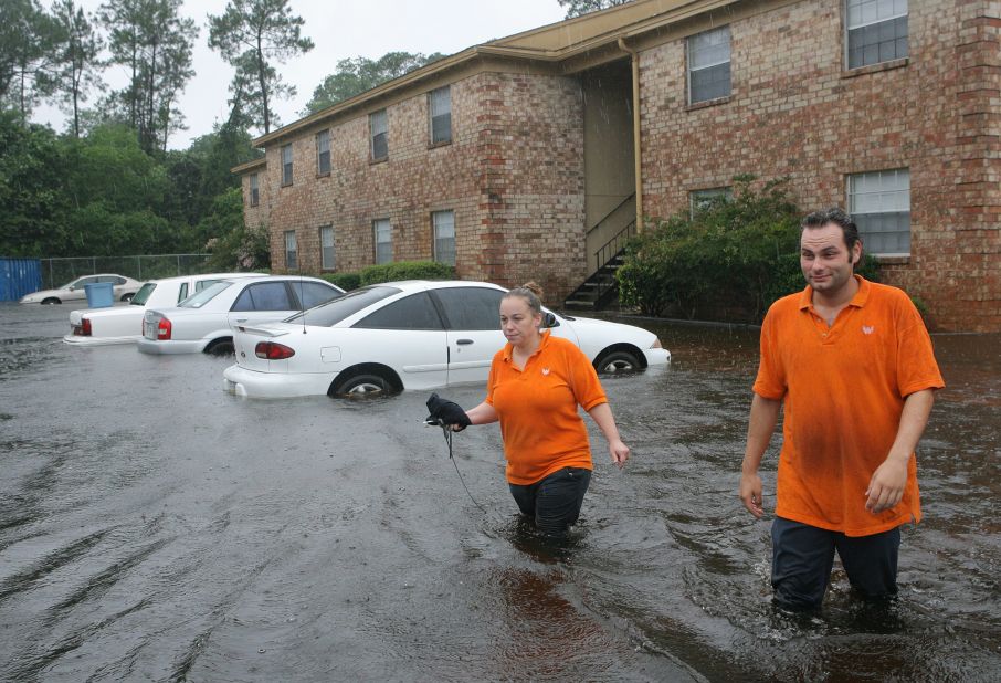 Lillian Murphy and co-worker Joseph Stanley wade through floodwaters Sunday at her Pensacola apartment complex.