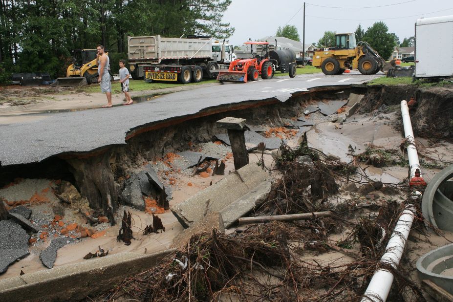The downpour leaves a Pensacola road washed out as Will Tollis, left, and his son Micah, 9, check out the damage Sunday, June 10. Authorities also warned of rip currents that could endanger anyone entering the surf along the Alabama and Florida coasts through Monday afternoon, June 11.
