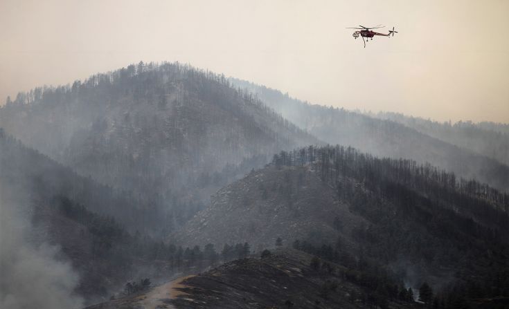 A firefighting helicopter surveys the High Park Fire for hot spots Sunday near Laporte as the wind-driven blaze spreads.