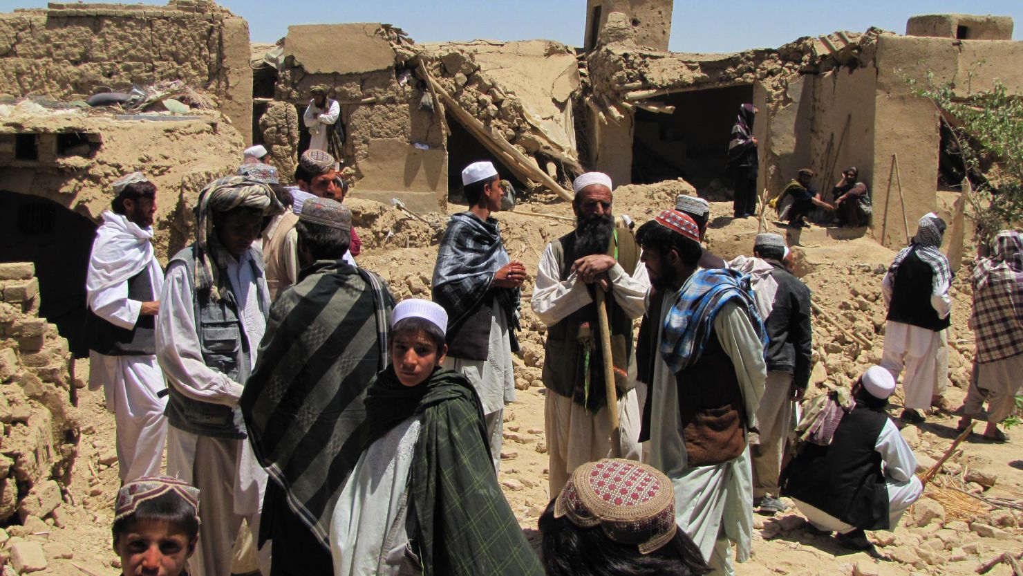 Afghan villagers stand outside a house which was hit by a NATO airstrike in Sajawand village, south of Kabul on June 6, 2012. 