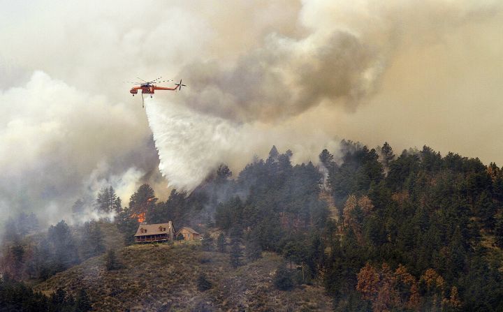 A helicopter drops water on a hot spot burning close to homes on Monday near Laporte, Colorado.