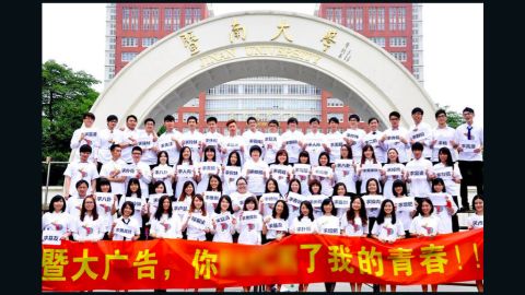 Students stand in front of a banner that reads "Jinan University Advertising Department, you f***ed my youth!" 