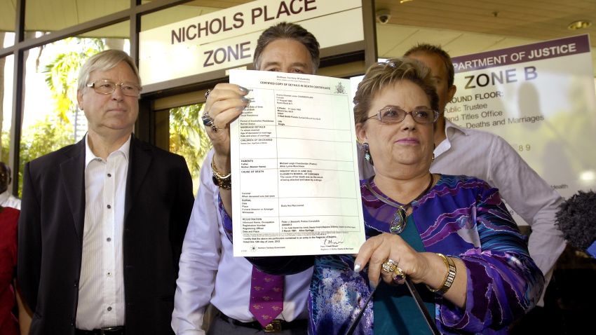 Lindy Chamberlain-Creighton shows off daughter Azaria's death certificate as ex-husband Michael Chamberlain (left) looks on after a coroner ruled that a dingo snatched baby Azaria Chamberlain from a tent in the Australian desert 32 years ago ending a case that caused a global sensation.
