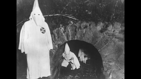 Ku Klux Klan members crawl out of a tunnel after a meeting in 1922.