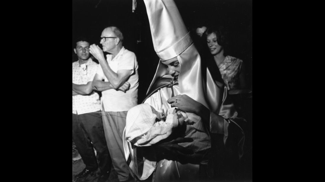 A woman dressed in Ku Klux Klan regalia holds her baby at a KKK meeting in Beaufort, South Carolina, in 1965.