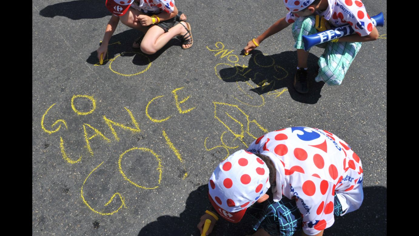 Young Armstrong fans write messages on the ground ahead of the 2009 Tour de France. He came in third place that year.