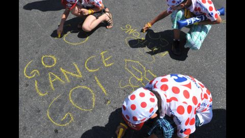 Young Armstrong fans write messages on the ground using yellow chalk ahead of the 2009 Tour de France. He came third that year.