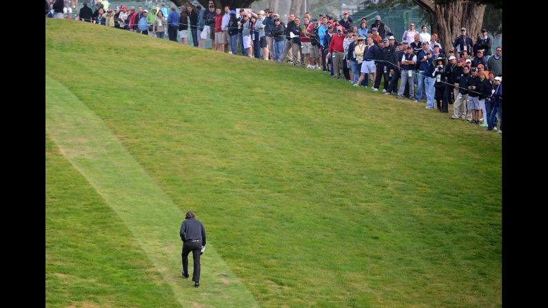 Spectators watch as Mickelson heads up the hill to the tee on the ninth hole.