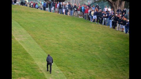 Spectators watch as Mickelson heads up the hill to the tee on the ninth hole. 