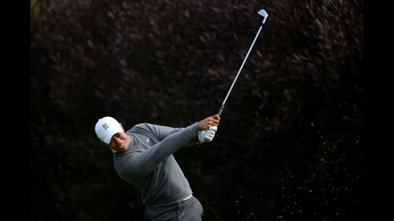 Woods, who was leading his group, hits his tee shot on the 13th hole Thursday.