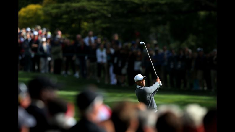 Tiger Woods watches his approach shot on the 18th hole during the first round  .