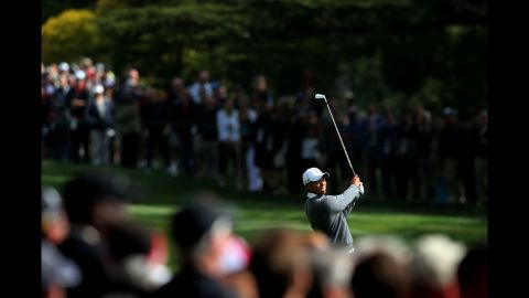 Tiger Woods watches his approach shot on the 18th hole during the first round  .