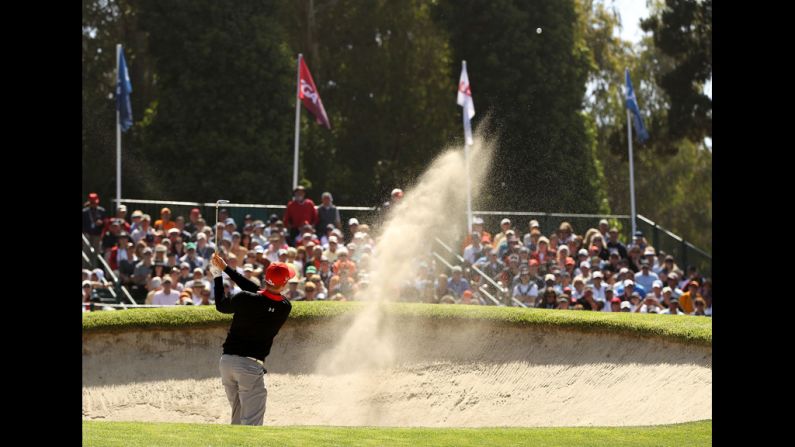 Hunter Mahan of the United States plays a bunker shot on the 17th hole during the first round.