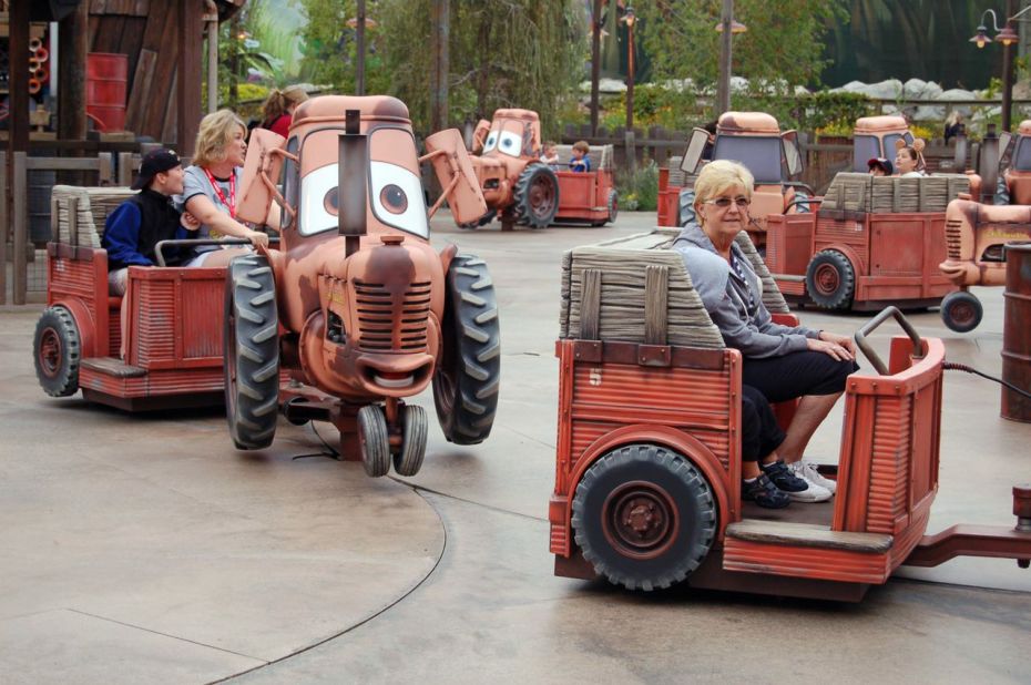 Riders of Mater's Junkyard Jamboree listen to cheerful songs as the tractors carrying them dance. 