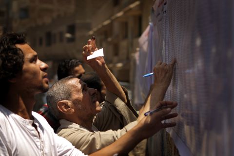 Egyptian Christian Coptic men check the voters' list Saturday outside a polling station in the Cairo Coptic neighborhood of Shubra.