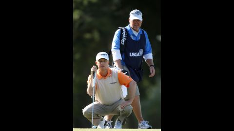 Caddie Scott Gneiser watches David Toms of the United States line up a shot during the second round.