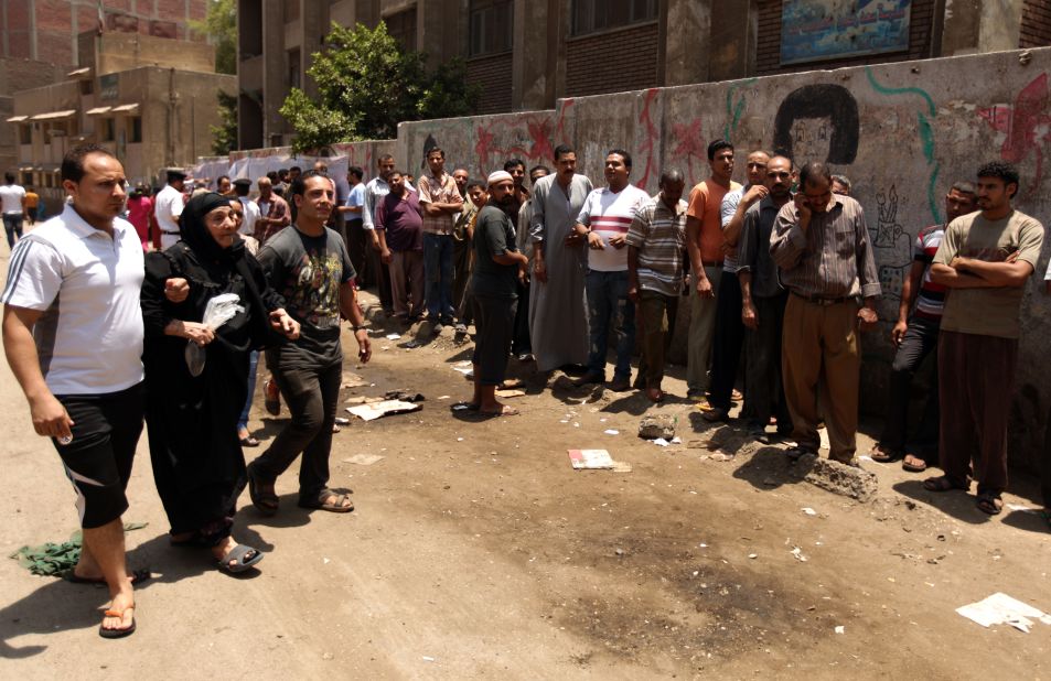 Egyptian Christian Coptic men help a woman reach a polling station in the Cairo Coptic Shubra neighborhood on Saturday, June 16.  Voters returned to the polls after Egypt's Supreme Constitutional Court ruled Thursday that the Islamist-led Parliament must be immediately dissolved.