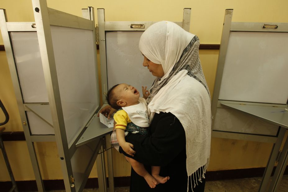 An Egyptian woman holds her baby as she prepares to vote at a polling station in Cairo.
