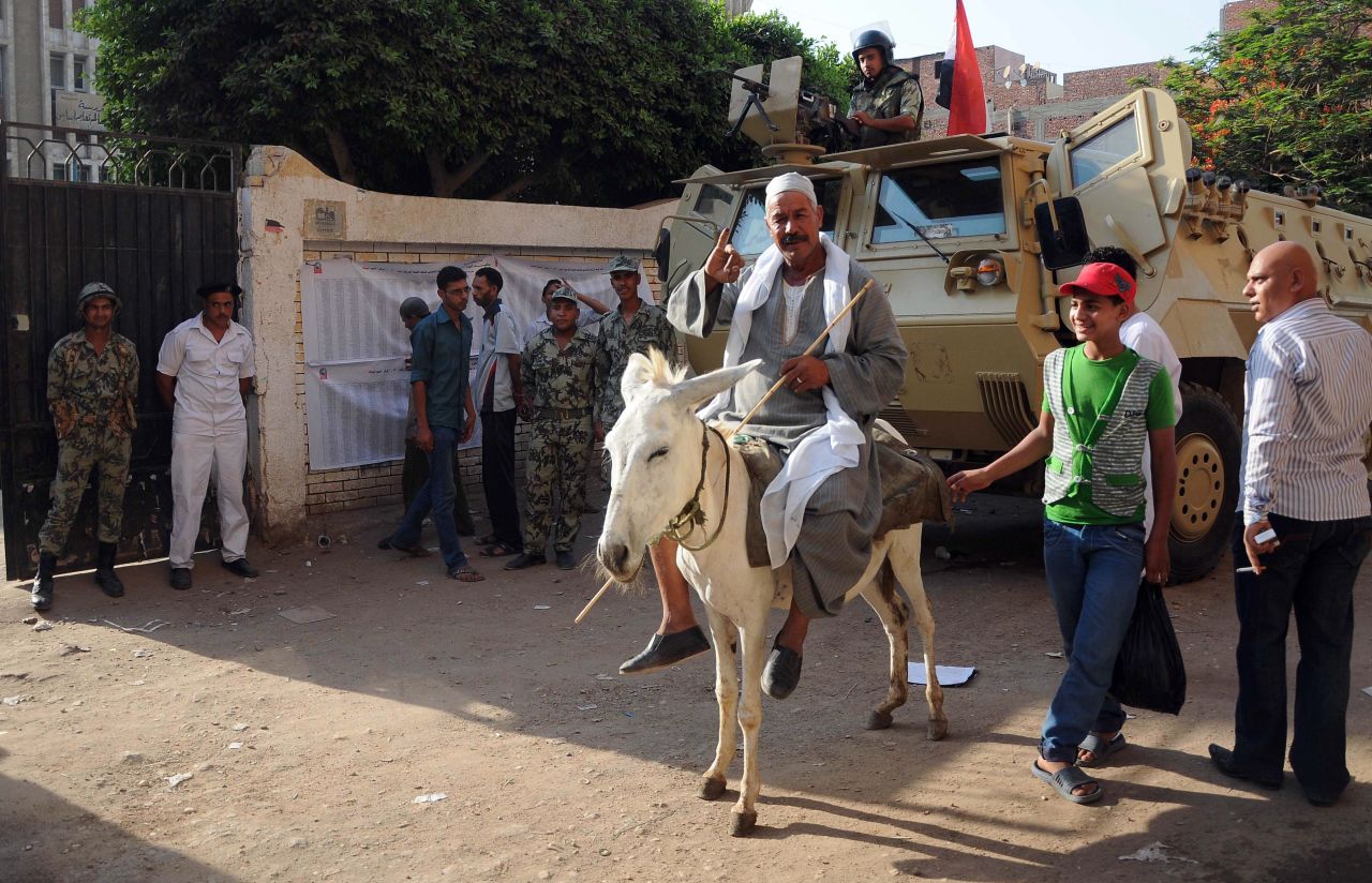 An Egyptian man on his donkey shows his ink-stained finger after casting his ballot.