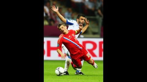 Andrey Arshavin of Russia falls under the challenge by Giorgos Tzavelas of Greece during the the match between Greece and Russia.
