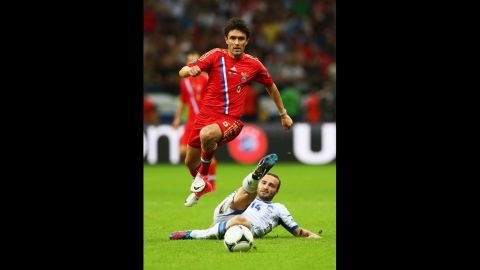 Yuriy Zhirkov of Russia jumps over the challenge by Dimitris Salpigidis of Greece during the match between Greece and Russia.