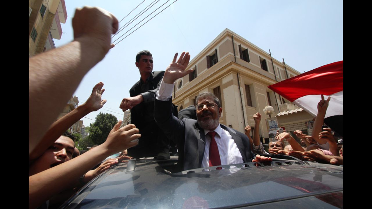 Egyptian Muslim Brotherhood candidate Mohammed Morsi, center, waves to his supporters as he arrives at a polling station to vote in the city of Zagazig.