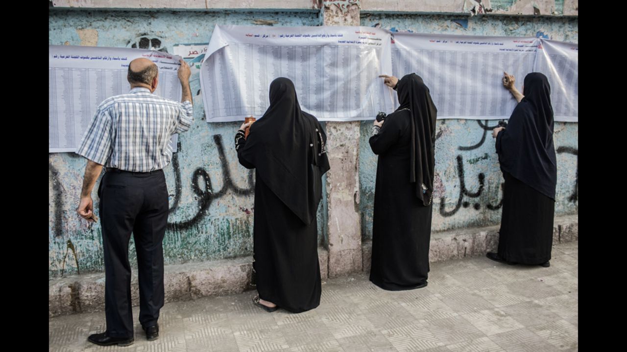 Egyptians check to see their names are listed before casting their votes at a polling station.