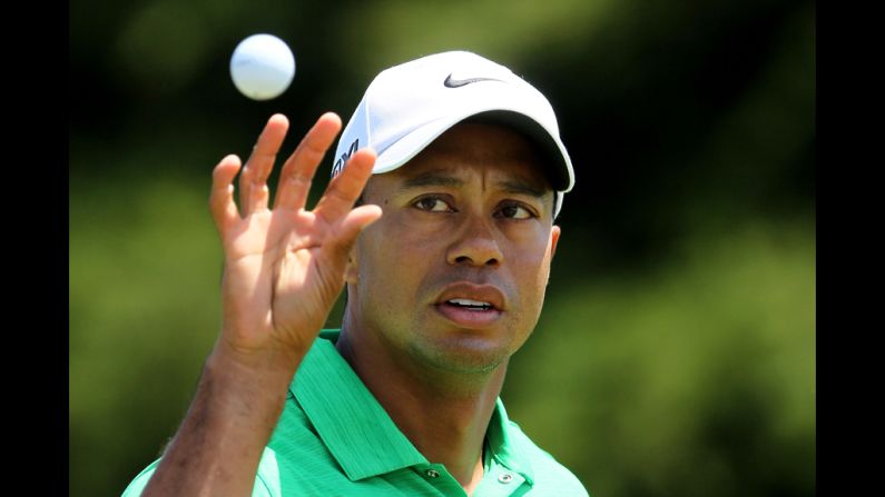 Tiger Woods of the United States reaches for a golf ball on the practice ground.