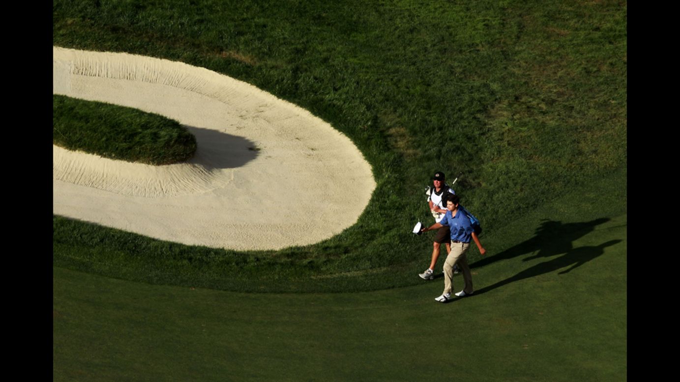 Amateur Beau Hossler of the United States walks to the 18th green with his caddie, Bill Schellenberg. 