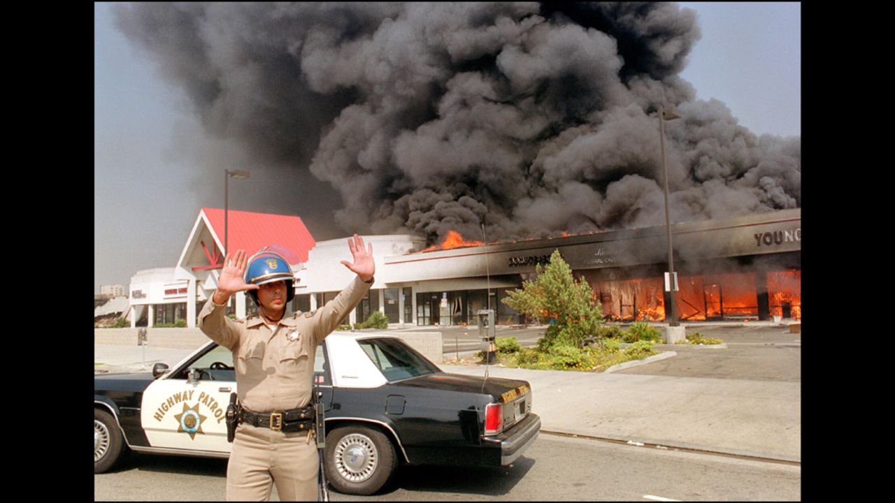 A California Highway Patrol officer directs traffic around a shopping center engulfed in flames on April 30.