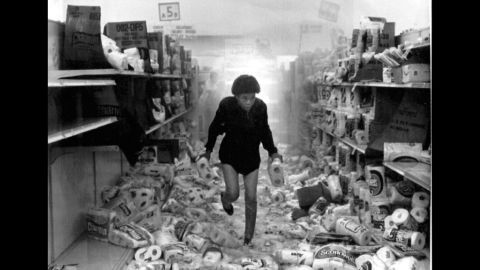 A woman runs out of a store that has been heavily looted as the overhead sprinkler system is triggered on May 1. More than 700 retail stores were damaged during the riots.
