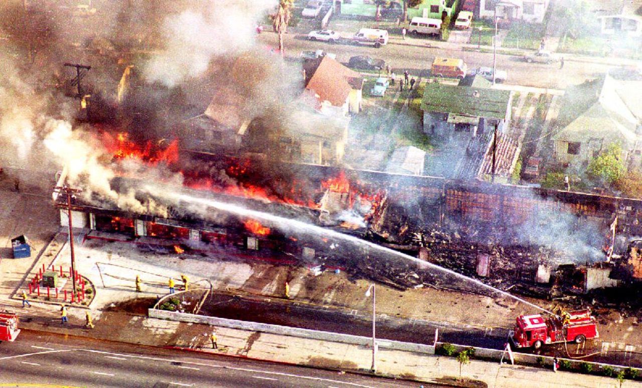Firefighters spray water on a burning building in south Los Angeles on April 30, 1992, a day after rioting broke out over  the acquittal of four white police officers charged with assault and the use of excessive force on Rodney King.