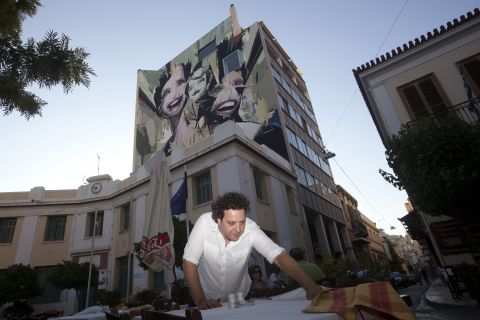 A restaurant worker clears tables in Psiri, a historic area of Athens.
