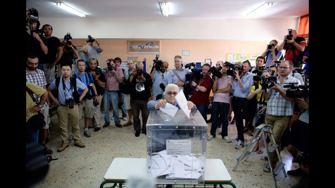 A woman, surrounded by media, casts her vote at a polling station in Athens.