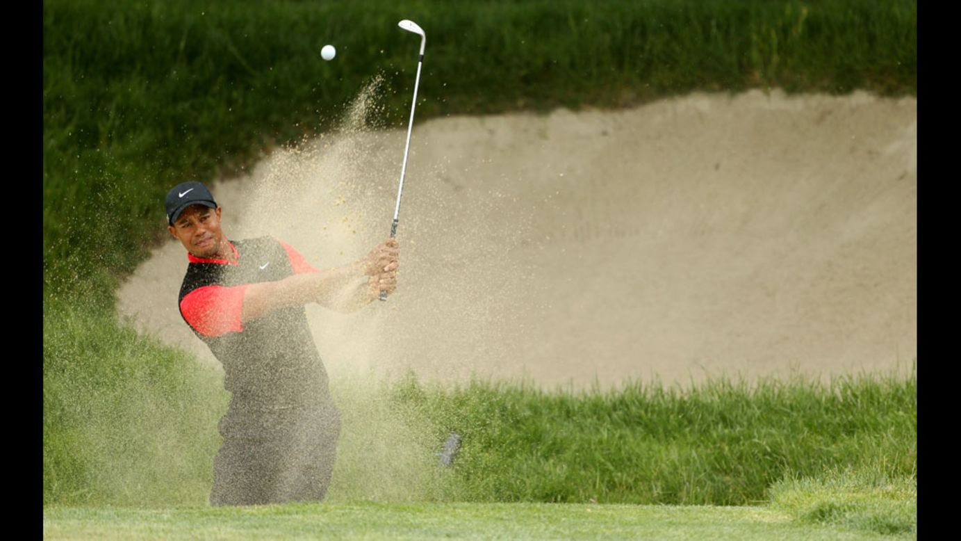 Tiger Woods hits a bunker shot on the first hole on Sunday.