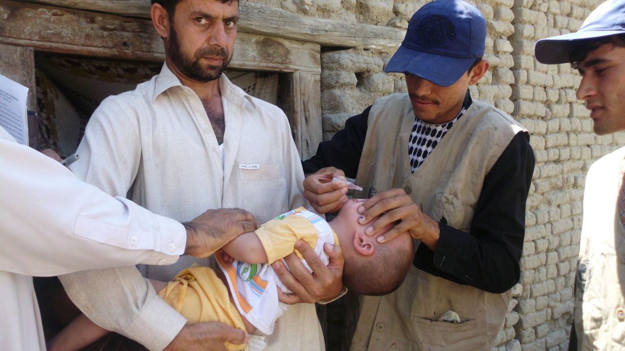 Afghan Health Ministry employees administer polio vaccine drops to a child in Laghman province on June 11, 2012. 