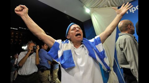 A New Democracy supporter celebrates as he watches the exit polls at the party's election campaign kisok in Athens.