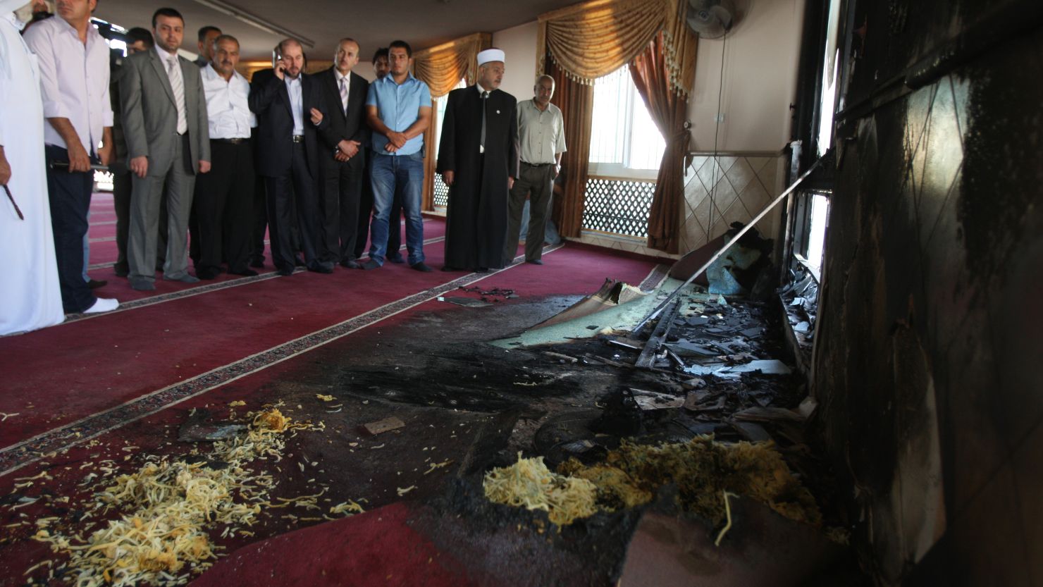 Palestinians from the village of Jabaa look at damage at a mosque which was partially set on fire overnight on June 19, 2012. 