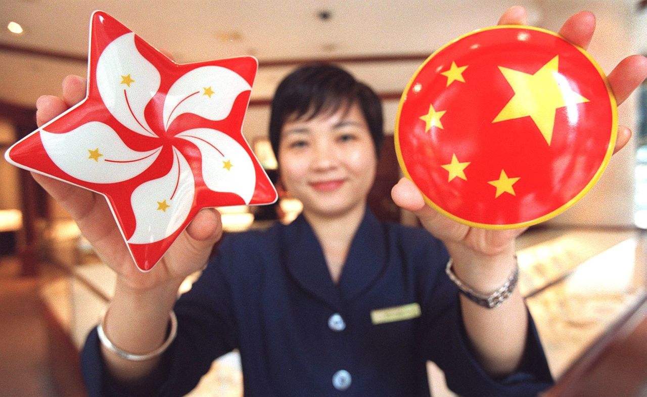 A shop assistant for luxury jeweler Tiffany's displays two porcelain souvenir boxes for sale, one featuring the new Bauhinia flower emblem of Hong Kong, the other the five stars of the Chinese flag.