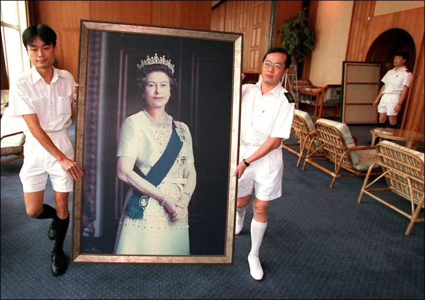 Two Royal Navy sailors remove a portrait of Queen Elizabeth II in HMS Tamar, the British Forces' Hong Kong headquarters, clearing the facilities for China's People's Liberation Army.
