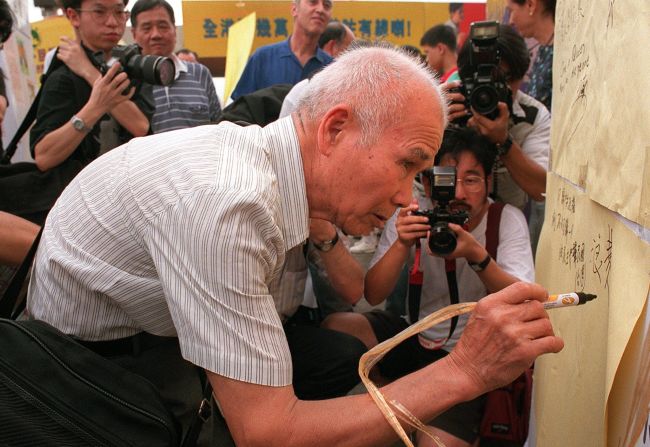 An elderly Hong Kong man signs an anti-communist board during a demonstration by activists of the Hong Kong Democratic Party on June 28, 1997.  Some residents feared democratic rights and freedoms would be eroded in Hong Kong under Chinese rule.