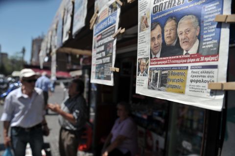 People read newspapers which detail the coalition talks on June 19. Greece hasn't had an elected government for 223 days.