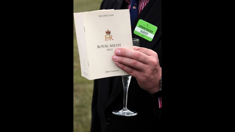 A visitor to Royal Ascot holds a race guide and a glass of Champagne.