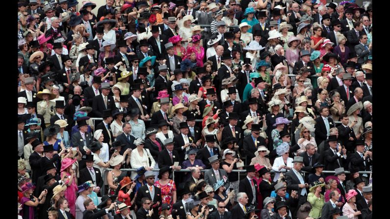 Race-goers from The Royal Enclosure watch the arrival of the royal family.