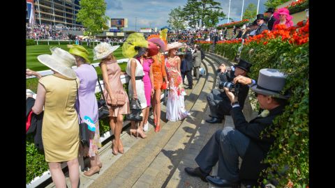 Photographers in top hats snap photos of Royal Ascot attendees.