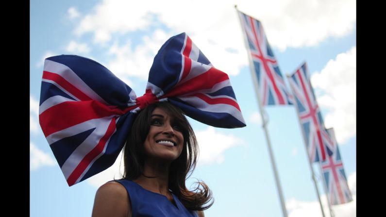 A race-goer wearing a flamboyant hat poses for the media.