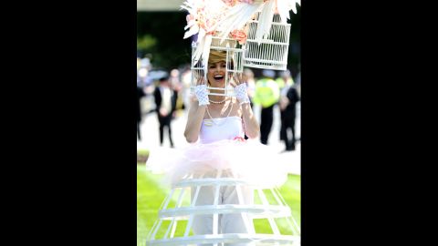 A woman wearing an elaborate hat designed to look like a bird cage attends day one of the races.