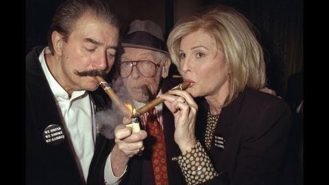 Milton Berle provides a light for his wife, Lorna, and Neiman in 1997.