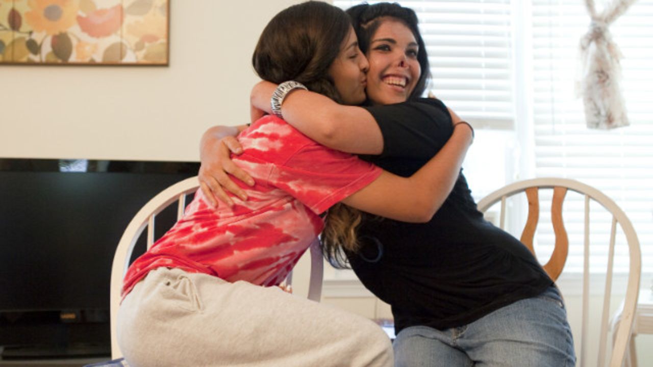 Aesha, right, hugs Miena, a high school honors student and athlete who has become a sister to her.